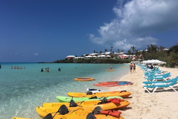 a group of lawn chairs sitting on top of a sandy beach