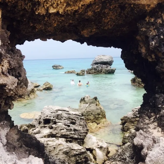 a rocky cliff with water and a mountain in the background